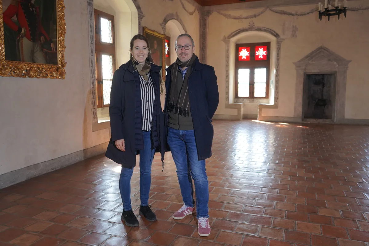 Eine Frau und ein Mann stehen in einem alten Saal.